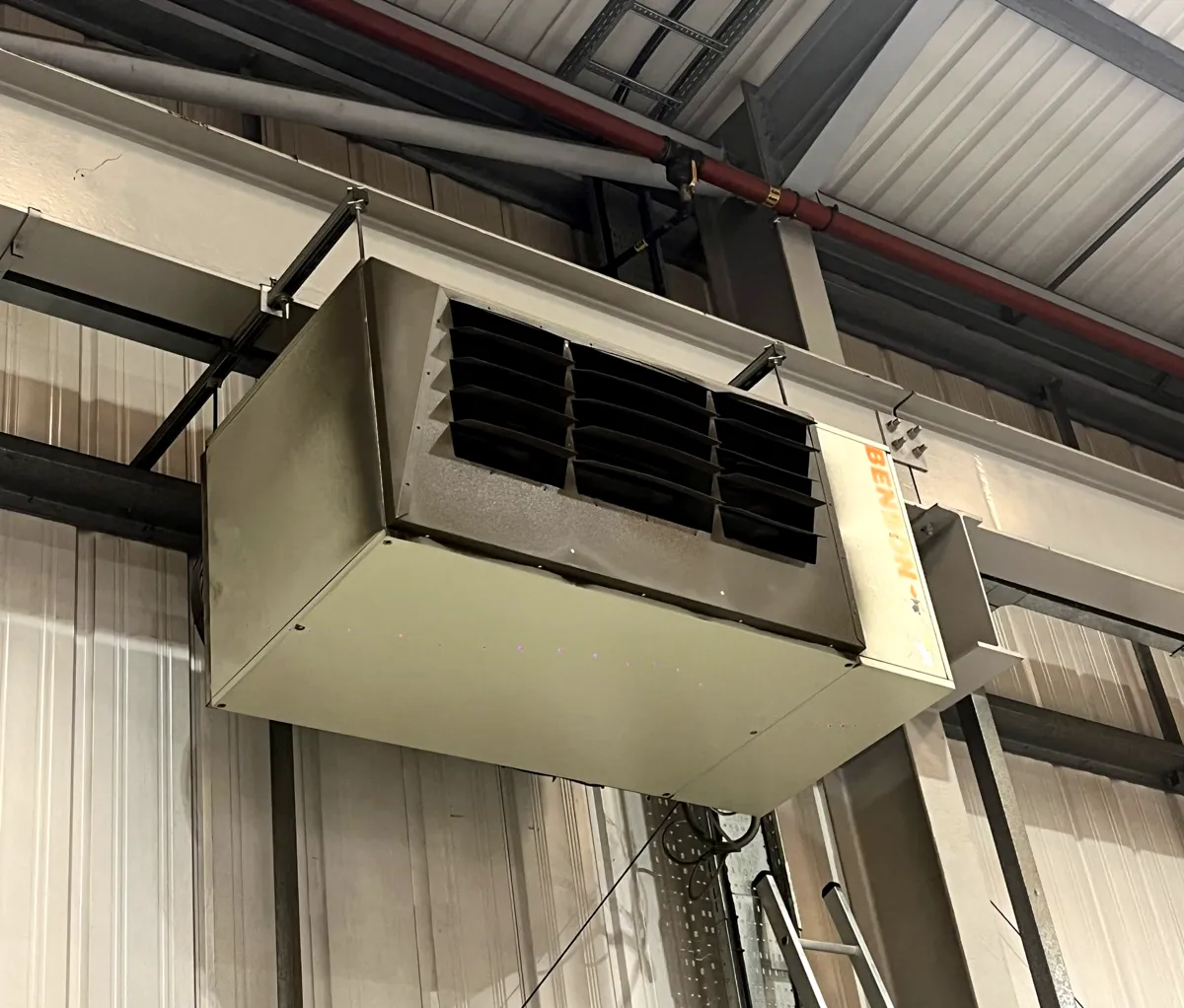 Benson gas-fired warm air unit heater hung from the steel roof frame of an industrial building