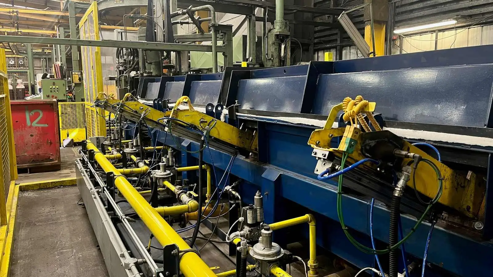 Industrial gas burner trains with yellow gas pipework on a factory production line
