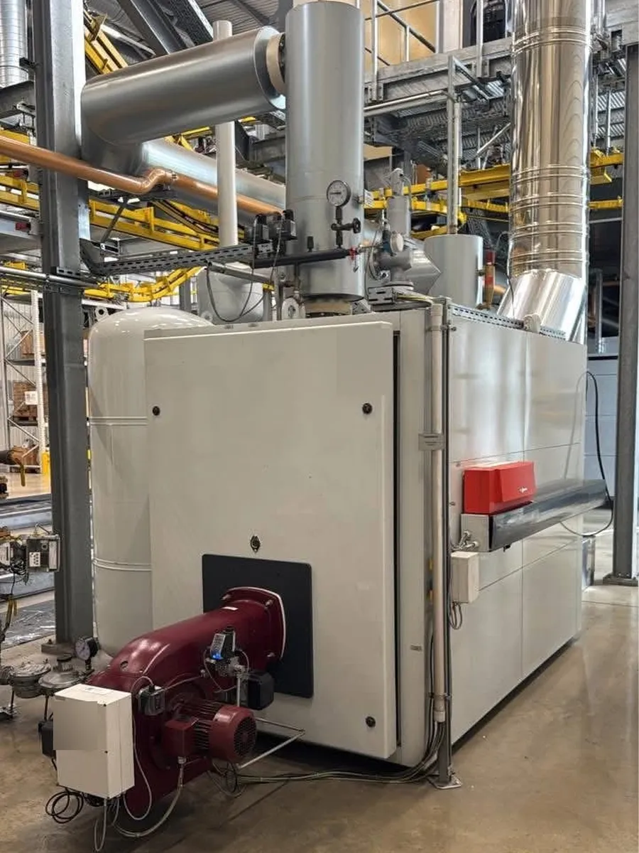 Large commercial boiler with a forced-draught burner and flue at an industrial site in Blackburn