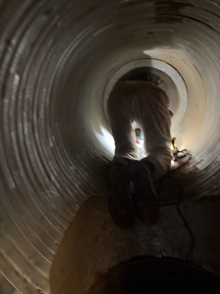 SMR engineer in protective overalls working inside industrial extract ductwork